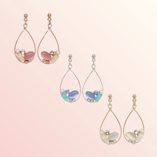 Set of teardrop-shaped earrings with gemstone-like beads on a light pink background