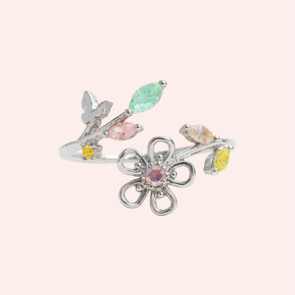 Silver ring with colorful gemstones on a light pink background