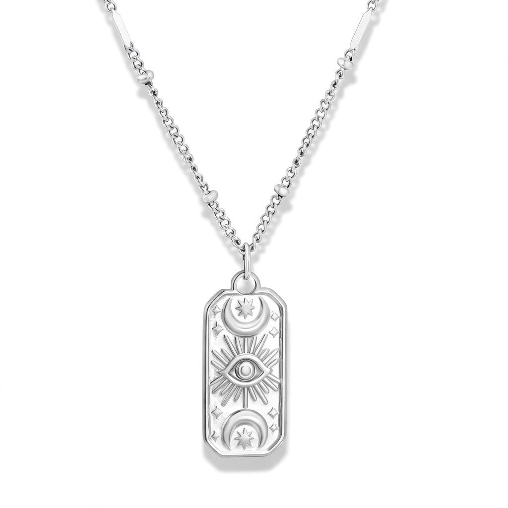A silver pendant necklace featuring a rectangular dog tag-style charm with engraved celestial and eye motifs, suspended from a silver chain against a white background.