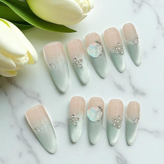 Decorative nails with opal stones and flowers on a marble surface with tulips.
