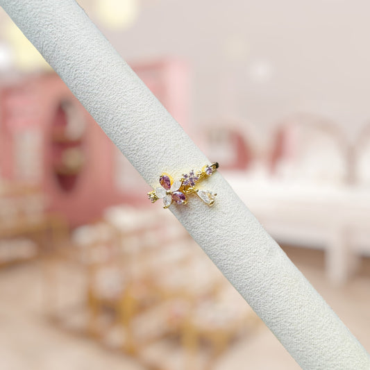 Gold ring with gemstones on a white stand against a blurred background