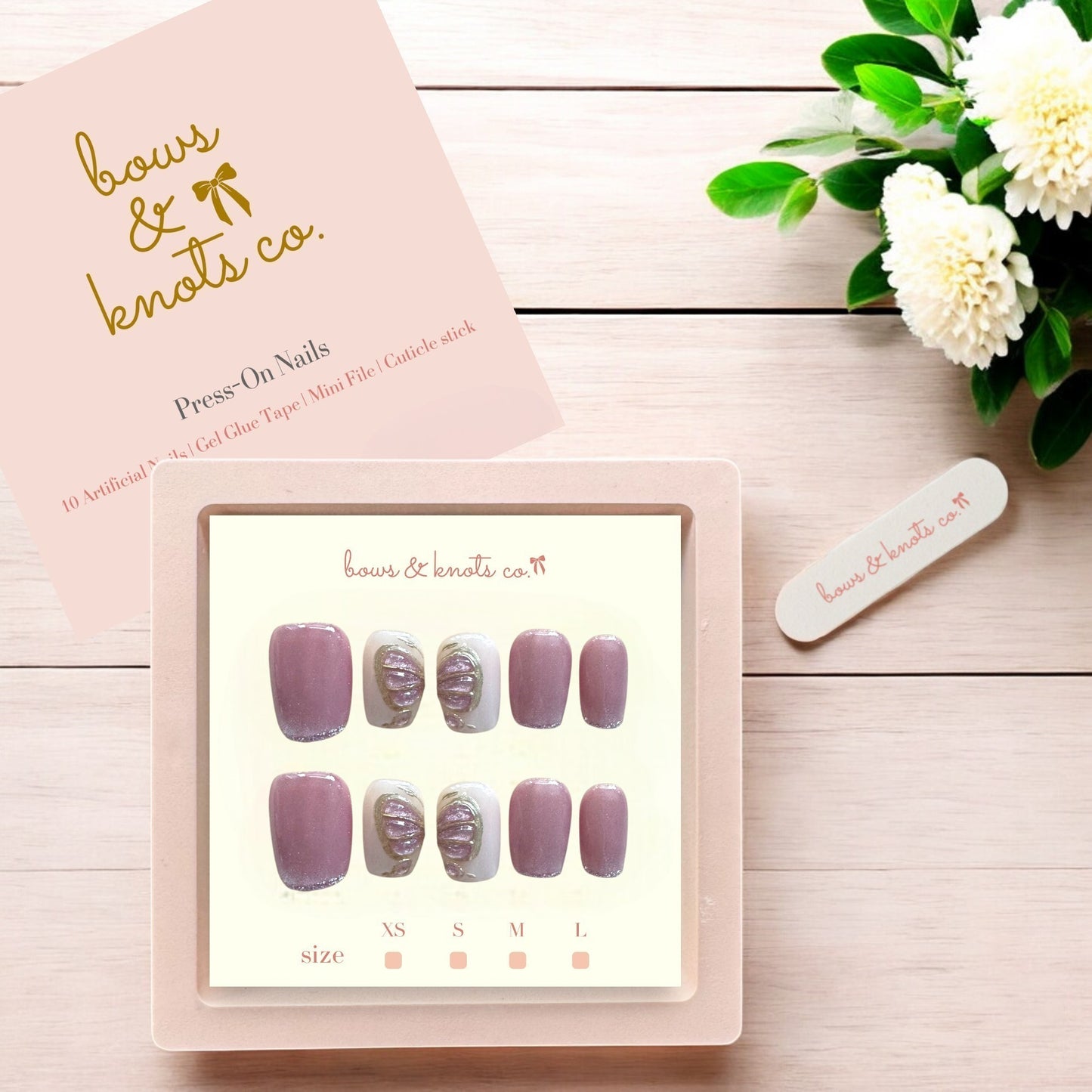 Display of press-on nails with a 'bows & knots co.' box on a wooden surface.
