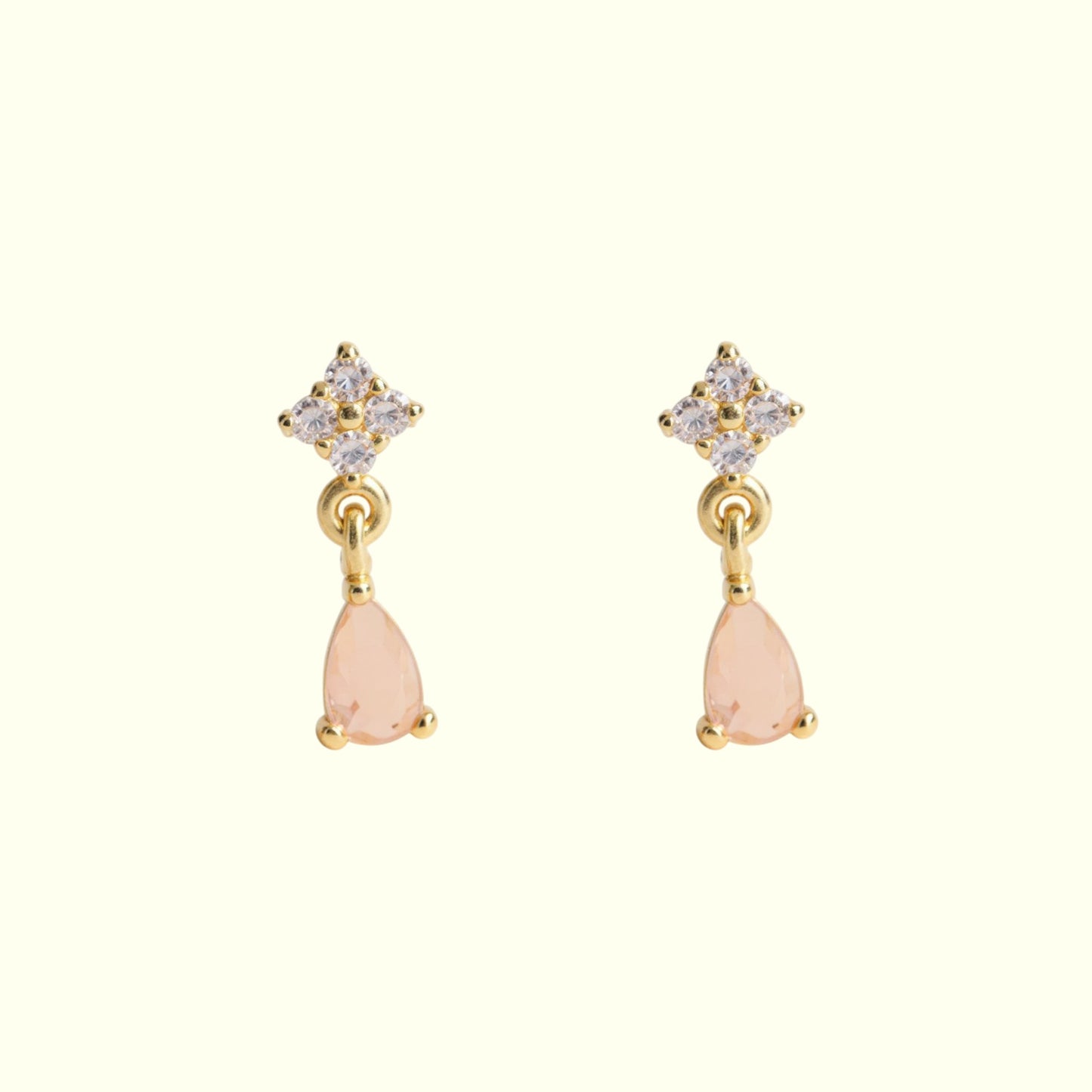 Pair of earrings with pink teardrop stones and gold accents on a white background