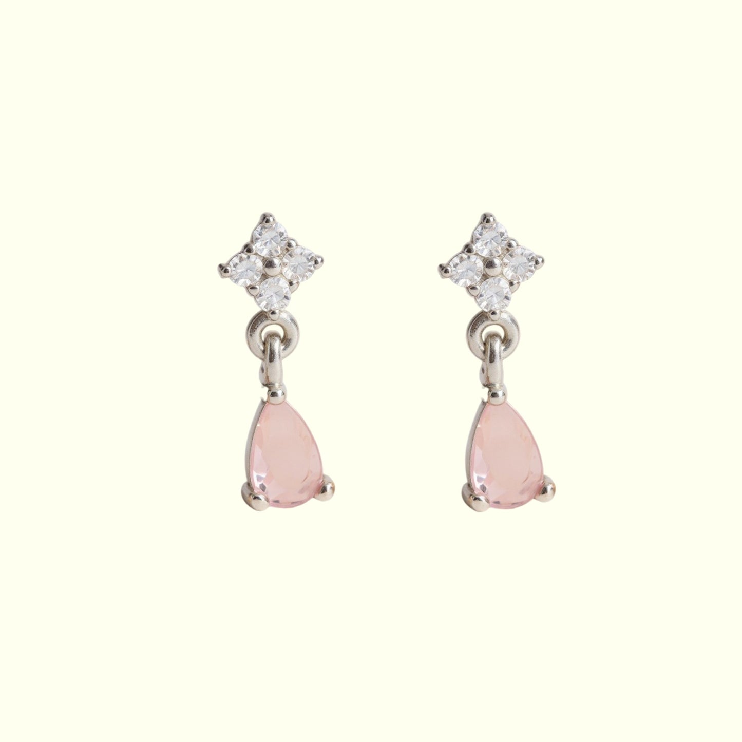Pair of earrings with pink teardrop stones and diamond-like tops on a white background