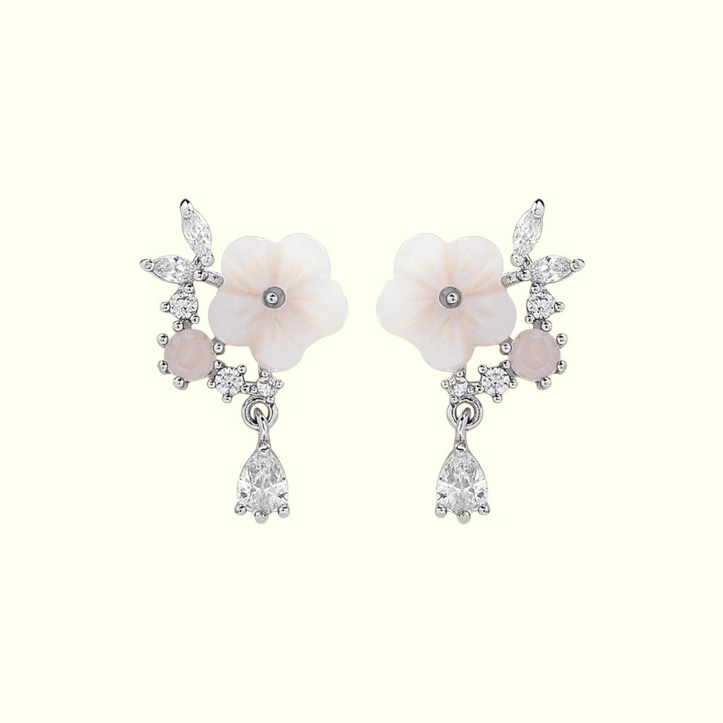 Pair of earrings with floral design and gemstones on a white background