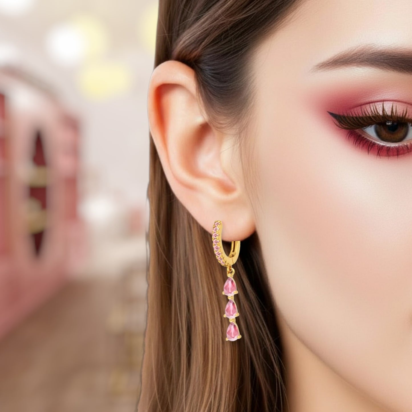 Close-up of a woman wearing gold hoop earrings with pink gemstones.