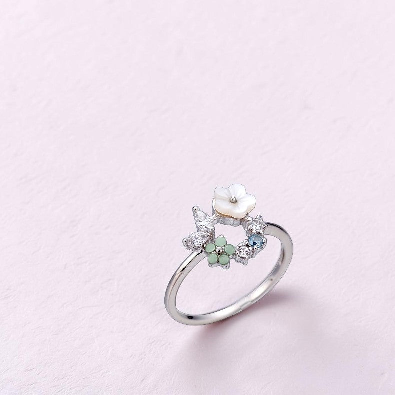 Silver ring with a pearl and gemstones on a light pink background