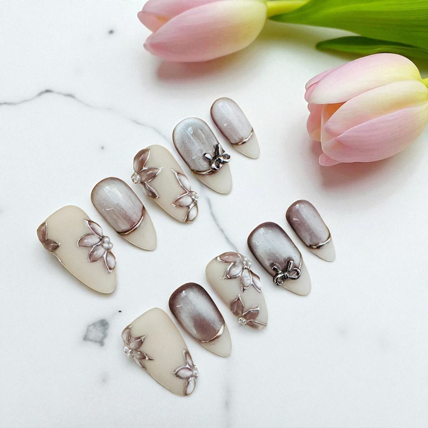 Nail art with floral designs on a white surface with tulips in the background