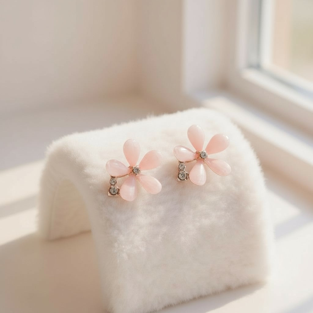 Pair of pink flower earrings on a white fur surface with a soft background