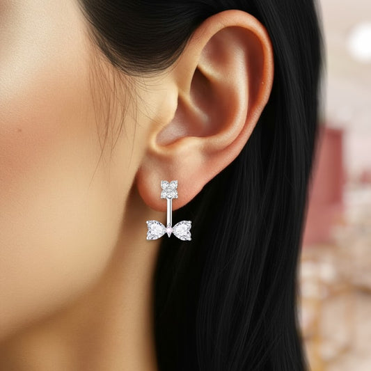 Close-up of an ear wearing a bow-shaped diamond earring with a blurred background