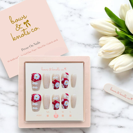 Box of press-on nails with floral design on a marble surface with tulips.