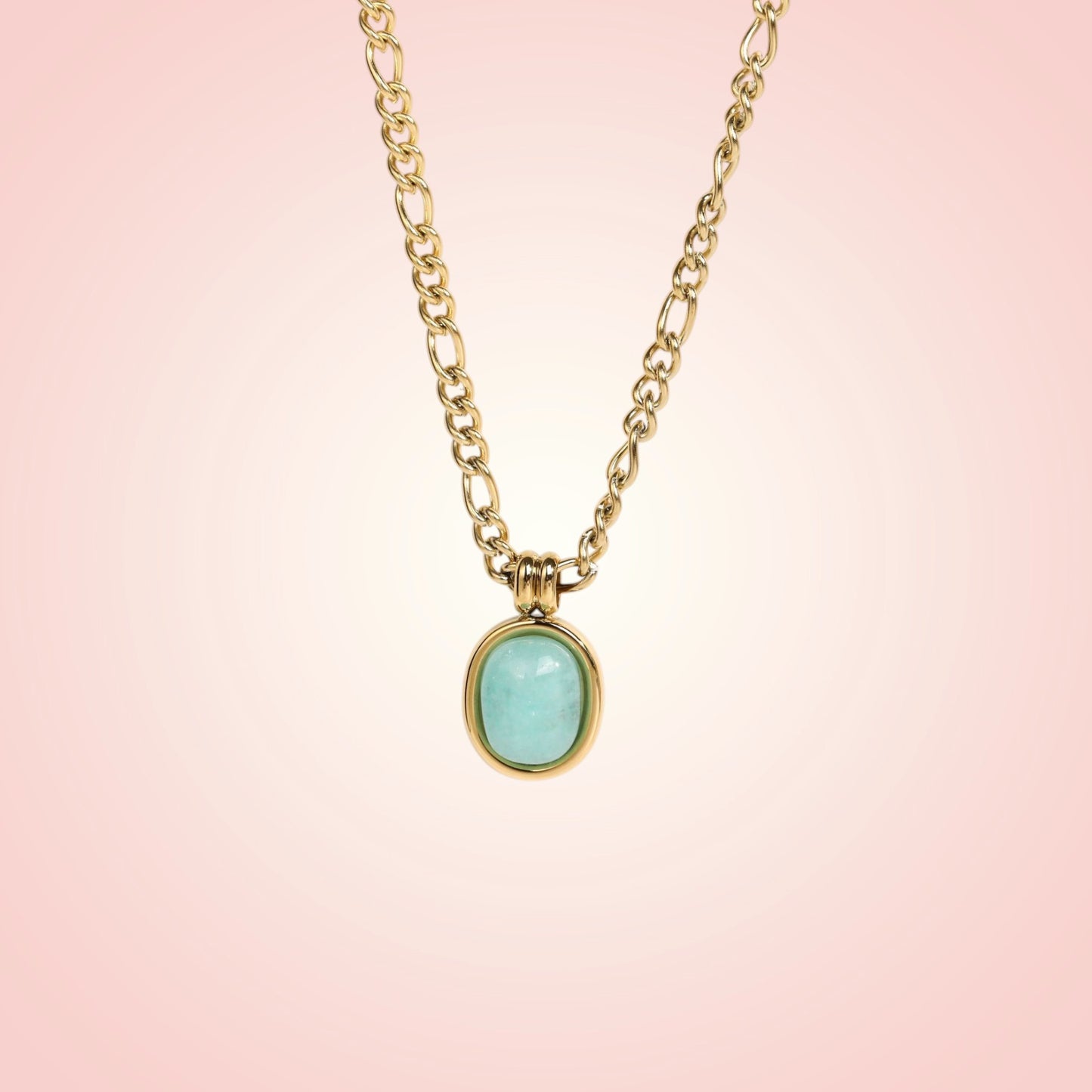 Gold necklace with a turquoise pendant on a pink background