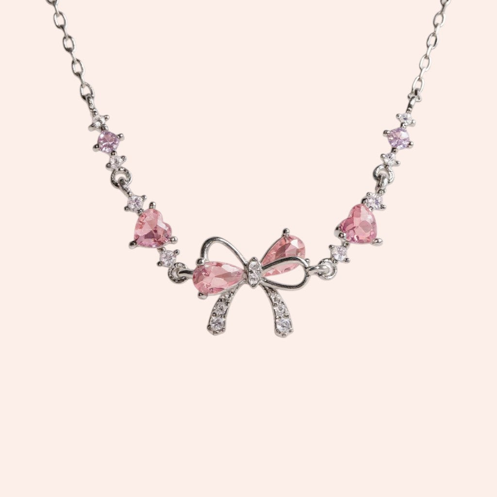 Bracelet with pink bow and heart-shaped gemstones on a light pink background