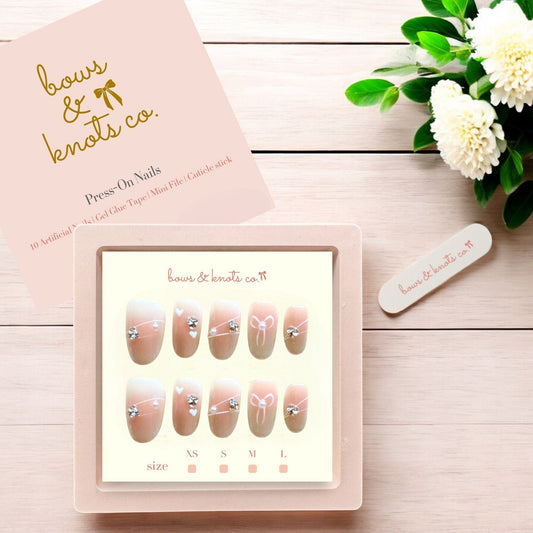 Press-on nails set with a pink box and floral decoration on a wooden surface