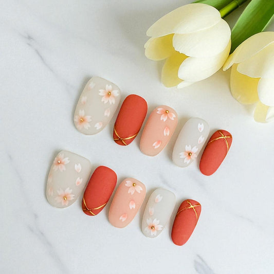 Nail art with floral designs on a white surface with yellow tulips.