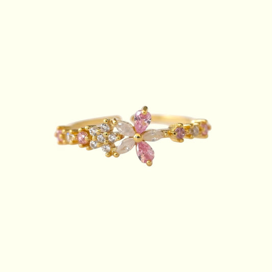 Gold ring with pink gemstones on a white background