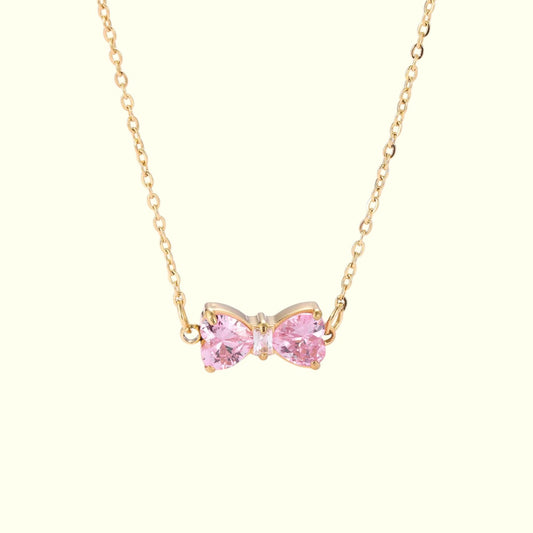 Pink bow-shaped necklace with gold chain on a white background