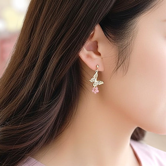 Close-up of a woman wearing a gold butterfly earring with pink gemstones.