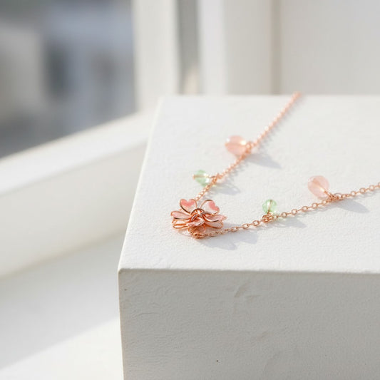 Delicate rose gold necklace with floral design on a white surface
