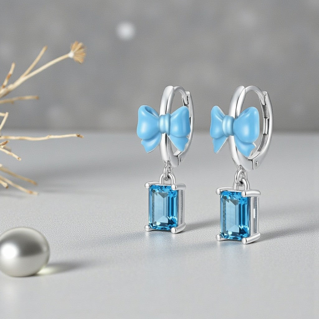 Earrings with blue bow and gemstones on a gray background