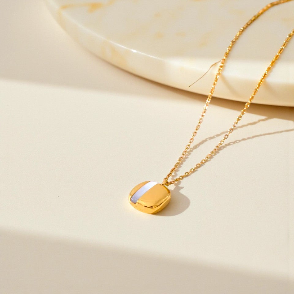 Gold necklace with a heart-shaped pendant on a beige background