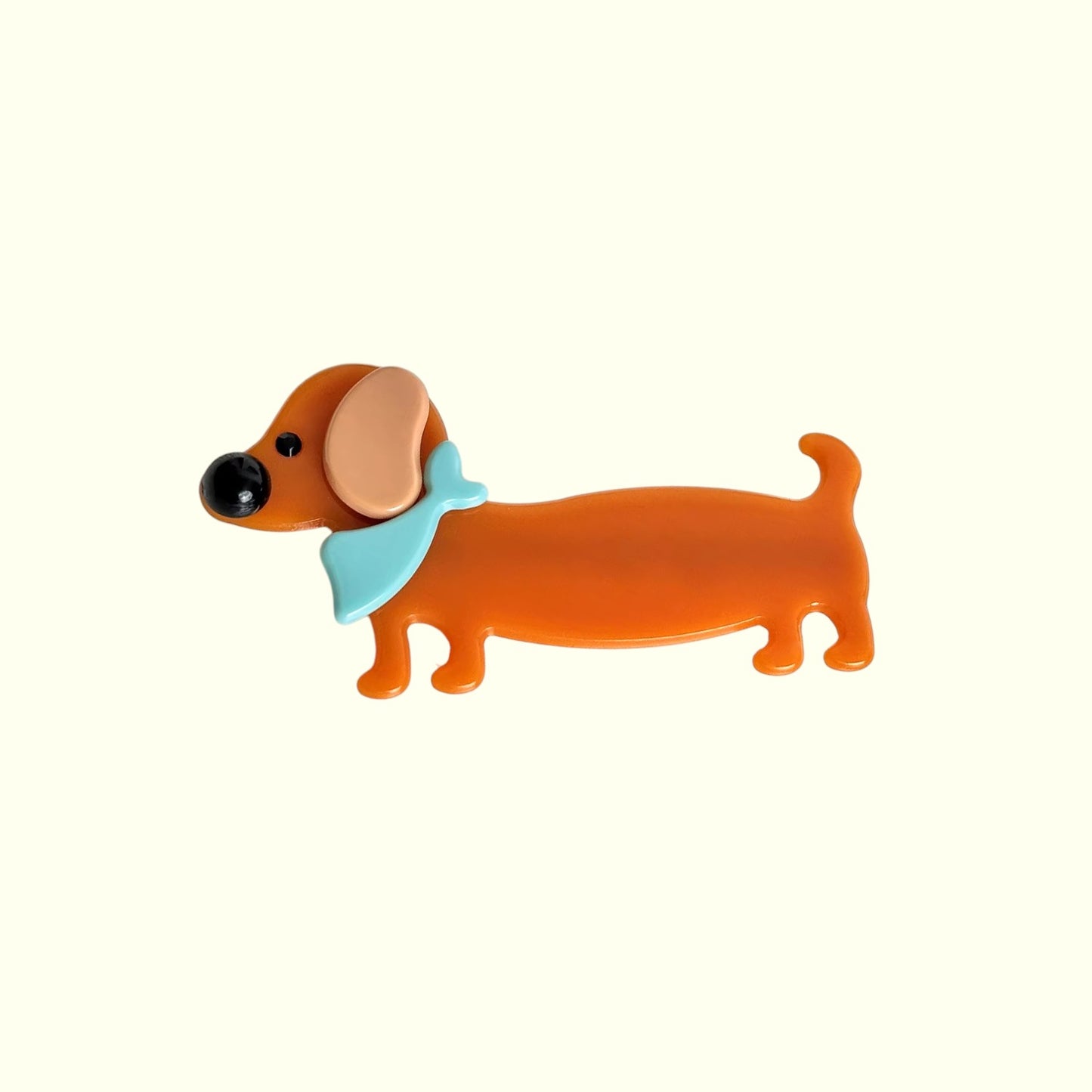 Dog-shaped hair clip with a blue bow tie on a white background