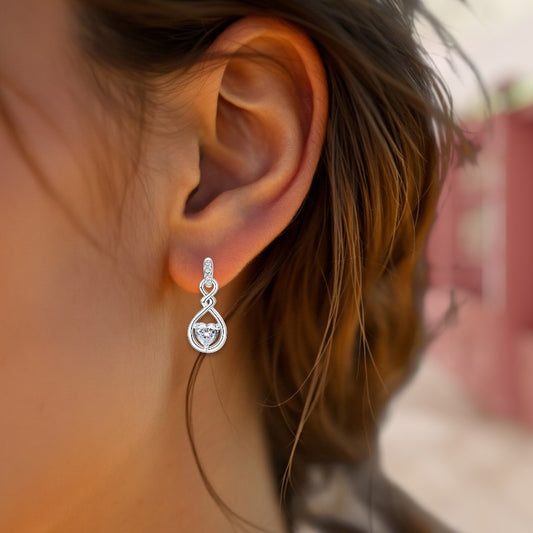 Close-up of a silver teardrop earring worn by a person with blurred background