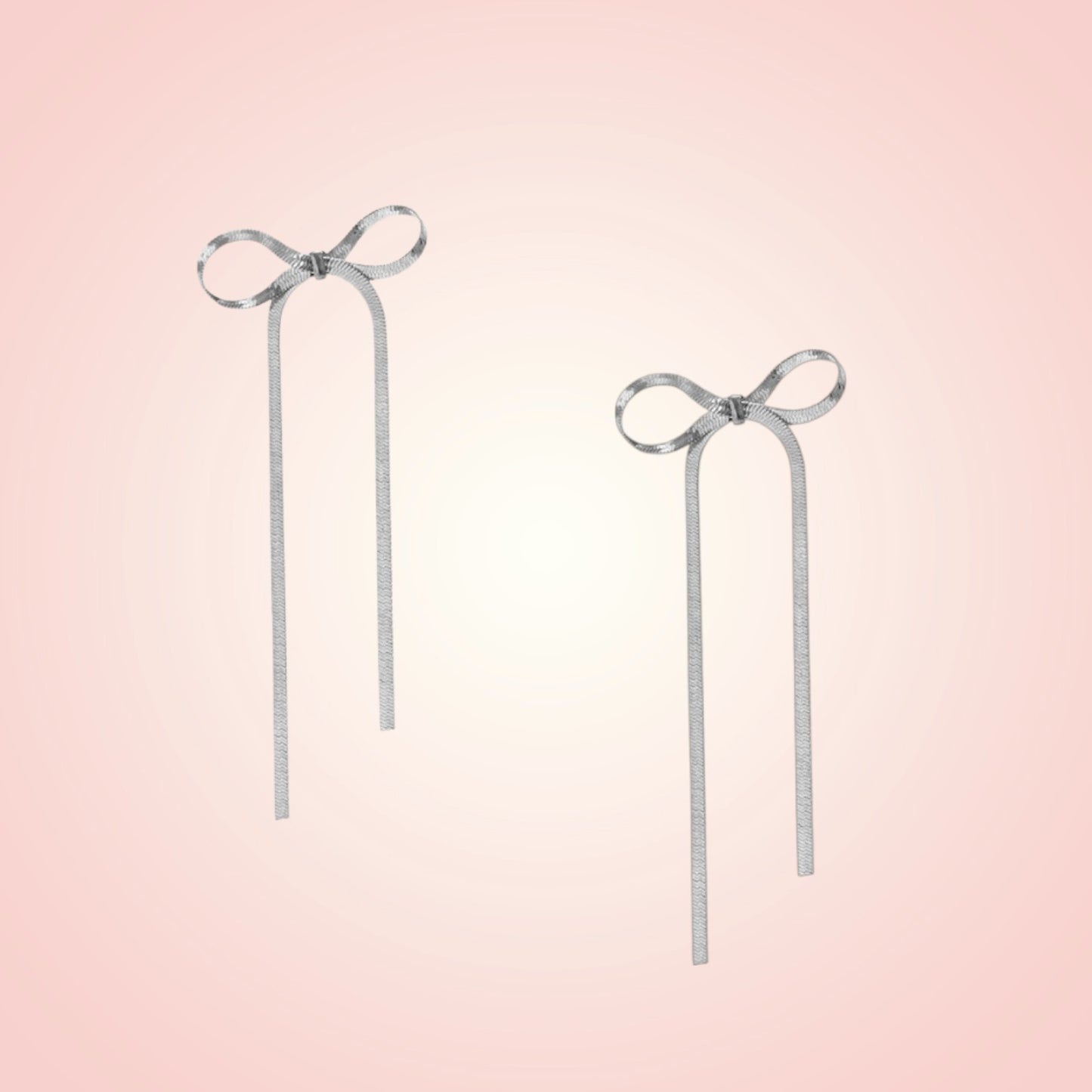 Pair of silver bow earrings on a gradient pink background