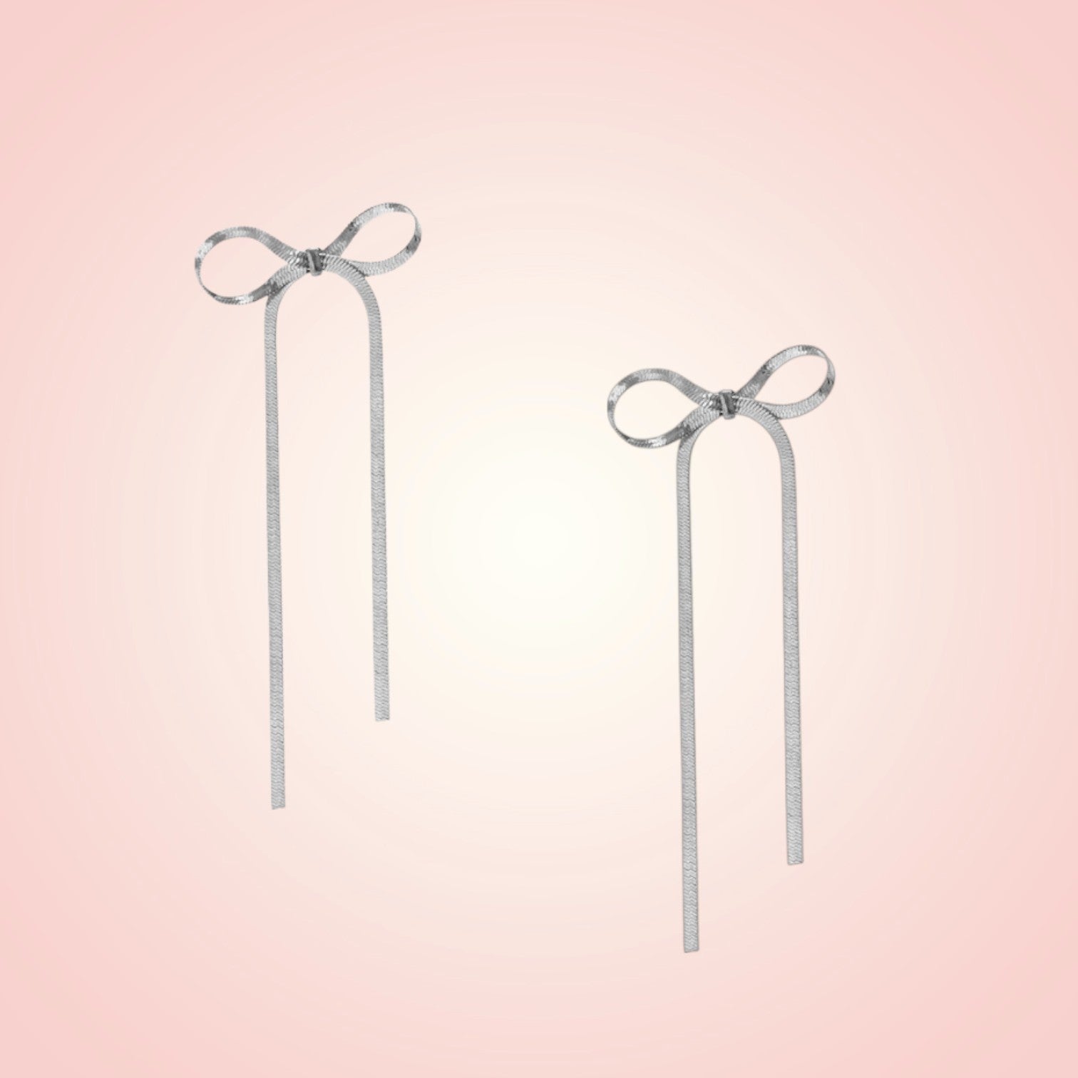 Pair of silver bow earrings on a gradient pink background
