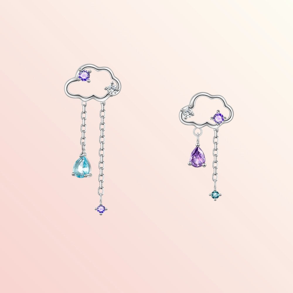 Pair of cloud-shaped earrings with gemstone drops on a pink background