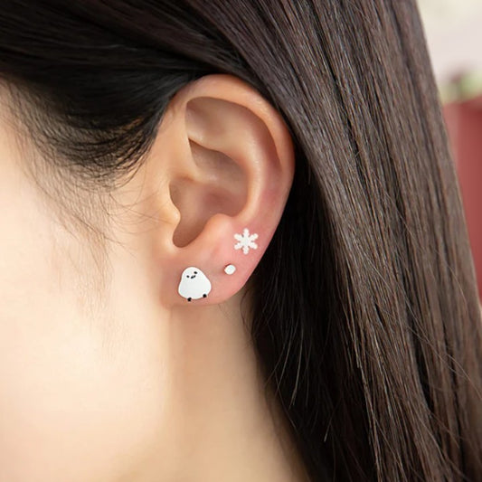 Close-up of an ear wearing a ghost-shaped earring with a star detail.