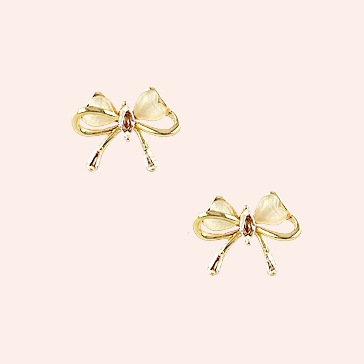 Gold bow-shaped earrings on a light pink background