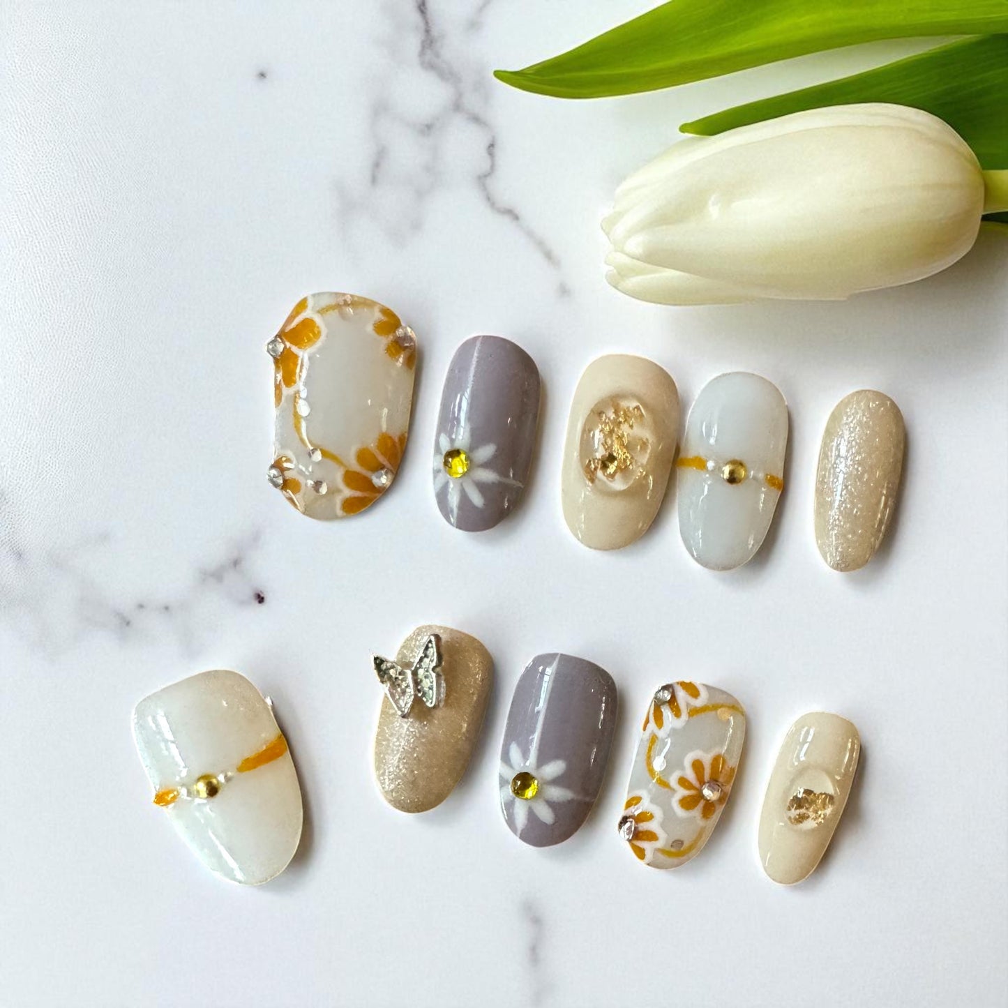 Set of nail art designs on a marble surface with a tulip.