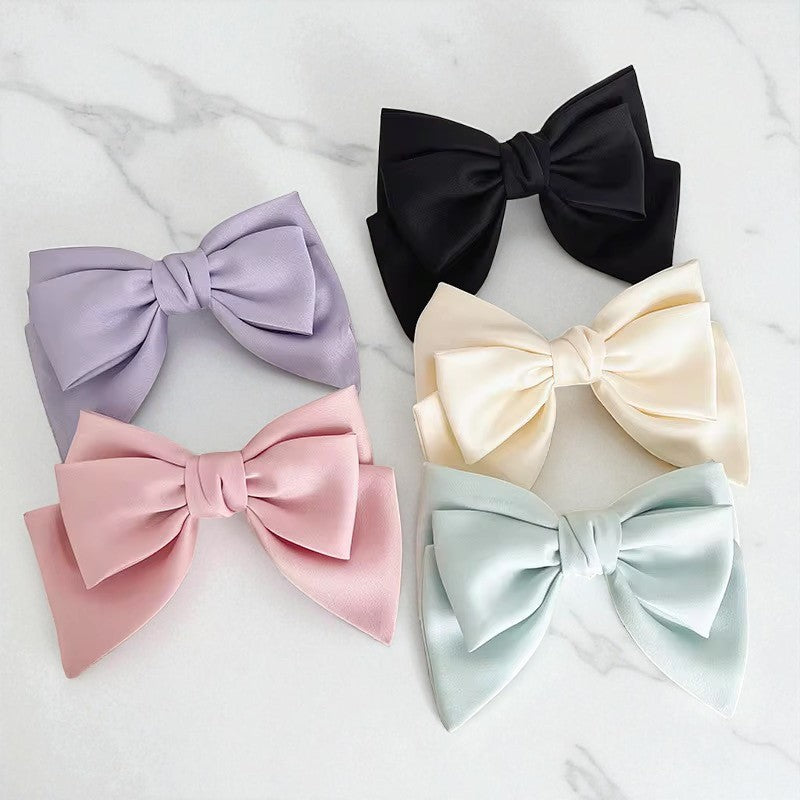 Five colorful satin hair bows on a light gray background