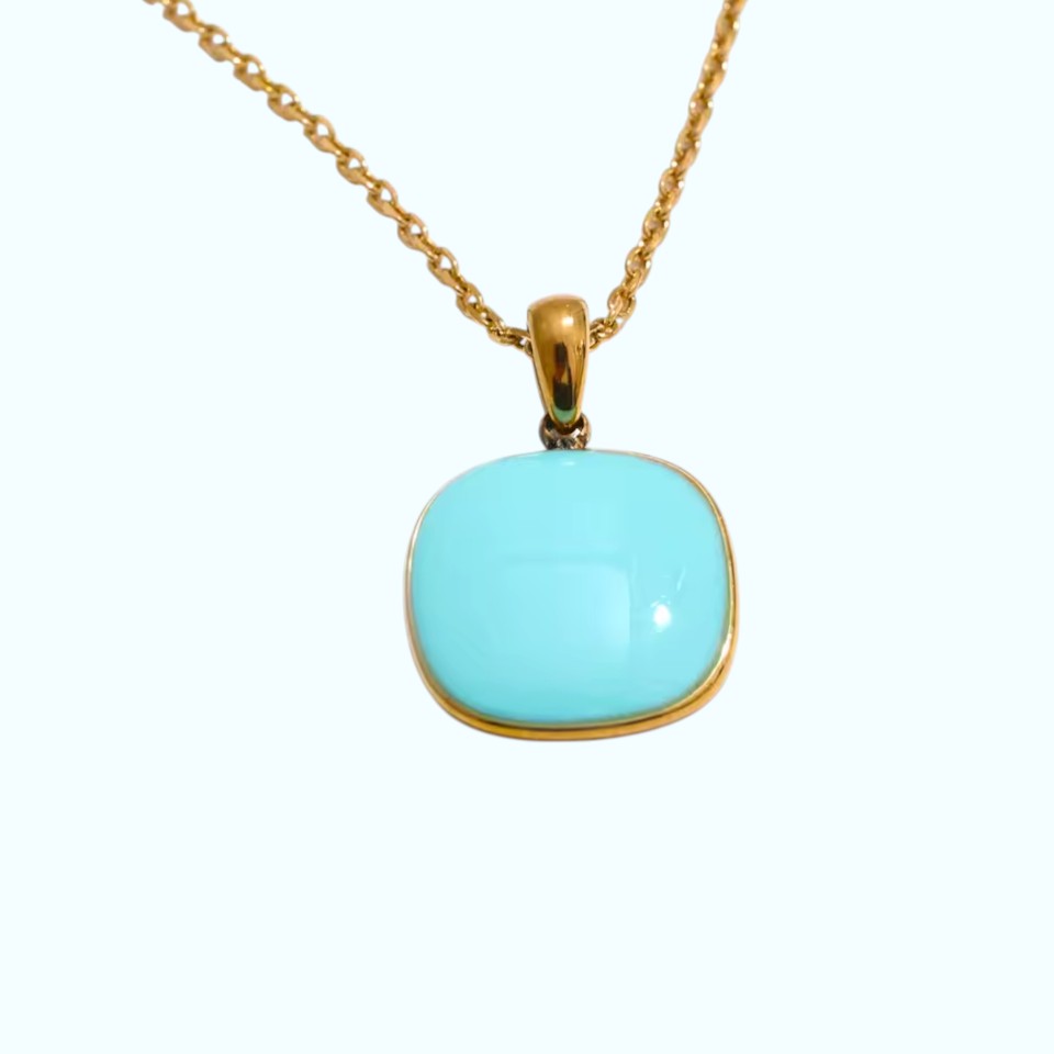 Turquoise pendant on a gold chain against a white background