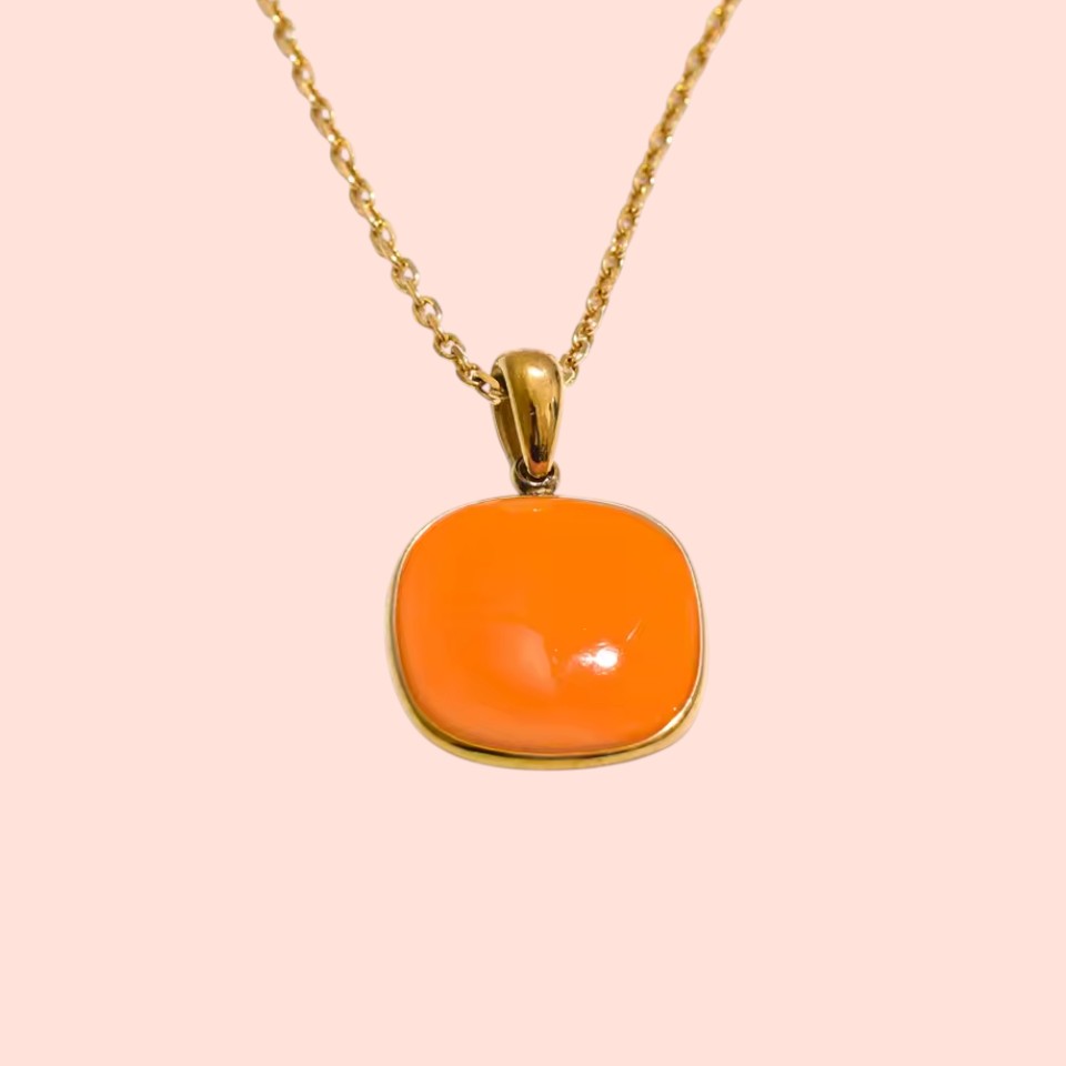 Necklace with an orange pendant on a pink background