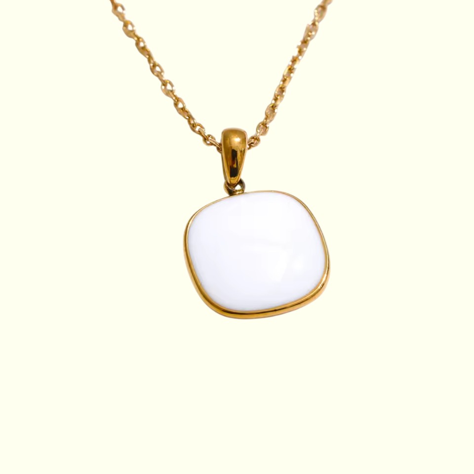 Gold necklace with a white pendant on a white background