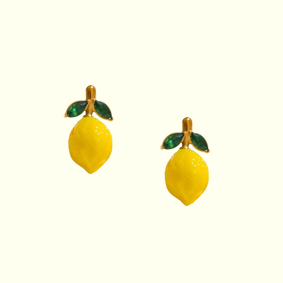 Lemon-shaped earrings with green leaves on a white background
