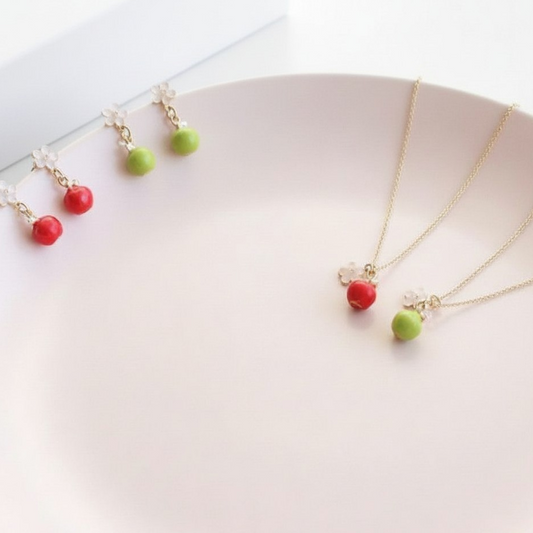 Two necklaces with red and green beads on a white surface