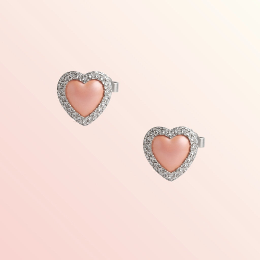 Heart-shaped earrings with pink center and silver border on a light pink background