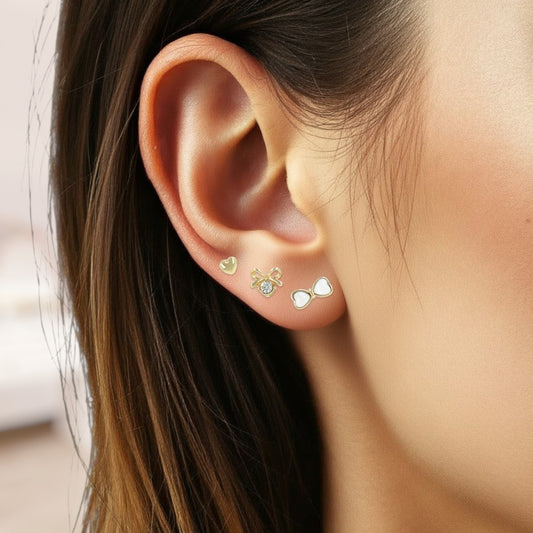 Close-up of an ear wearing three small earrings with a blurred background