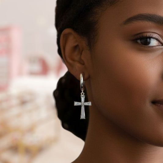 Close-up of a woman wearing a silver cross earring with a blurred background