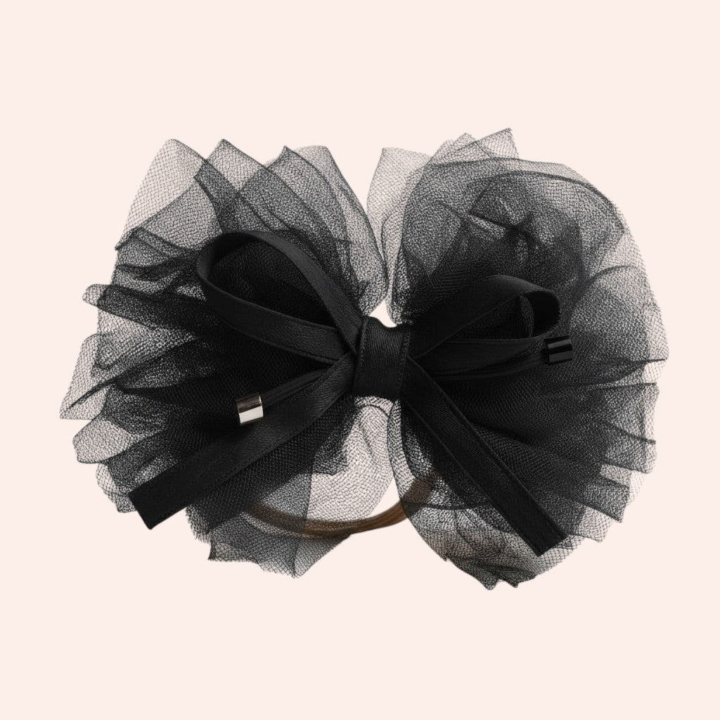 Black tulle hair bow with a black ribbon on a beige background