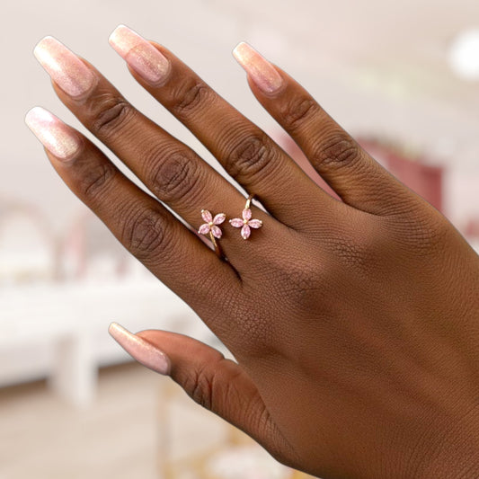 Hand wearing a pink floral ring with blurred background