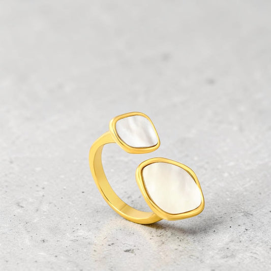 Gold ring with two large white stones on a light gray background