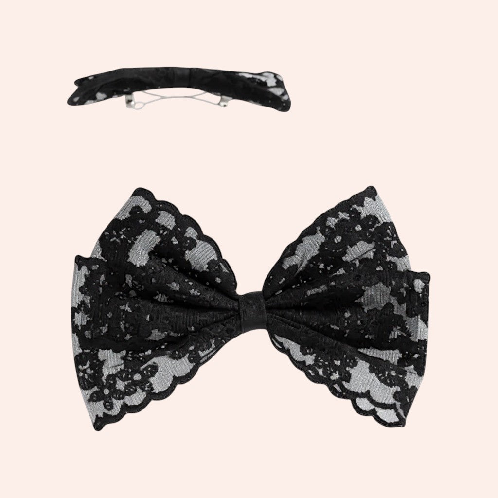 Black lace bow hair clip on a light pink background