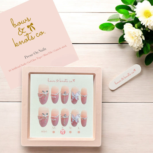 Press-on nails set with a pink box and decorative flowers on a wooden surface