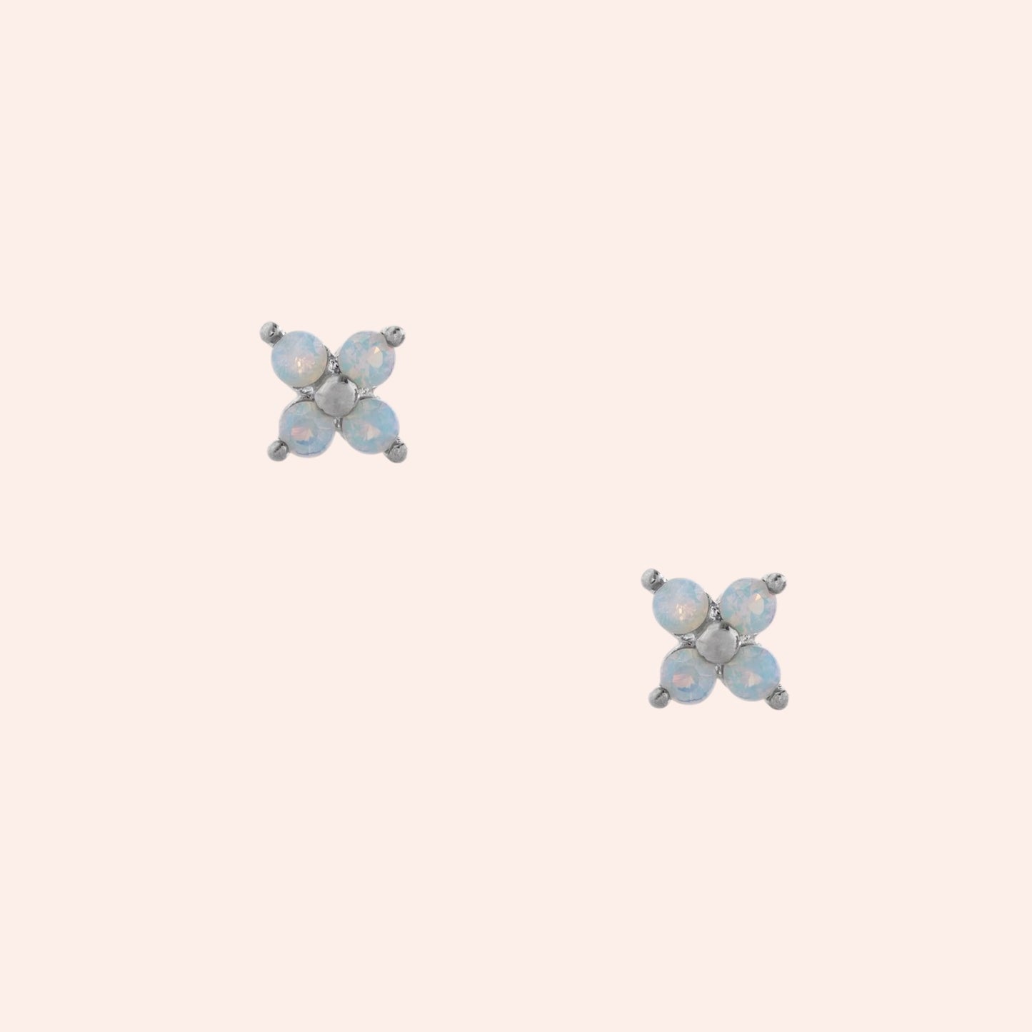 Pair of butterfly-shaped earrings with blue gemstones on a light beige background