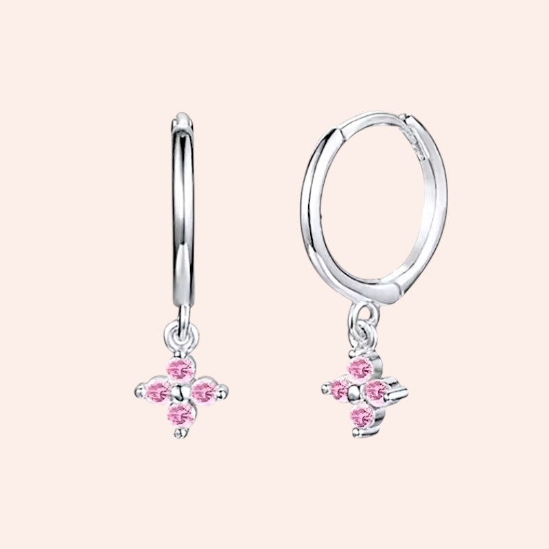 Silver hoop earrings with pink gemstone charms on a light pink background
