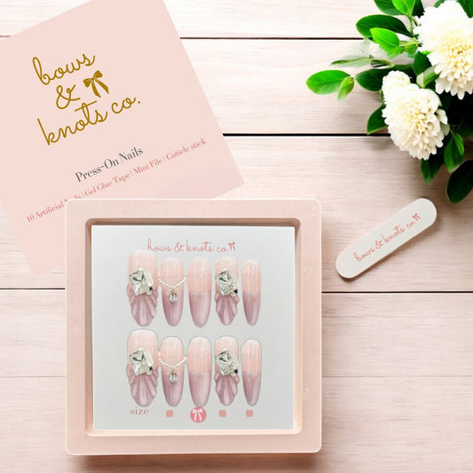 Press-on nails set with decorative elements on a wooden surface, featuring 'bows & Knots Co.' branding.